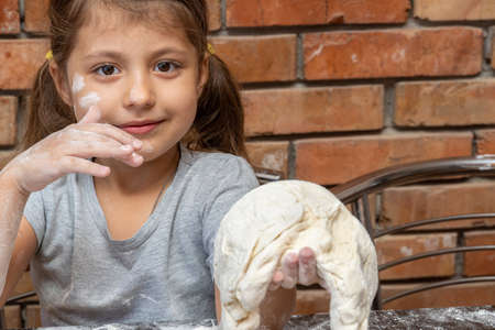 cute little girl kneading dough, preparing dough for bakingの写真素材