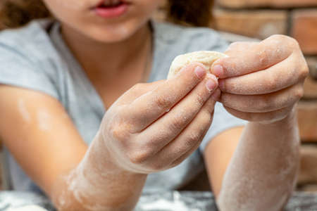 cute little girl kneading dough, preparing dough for bakingの写真素材