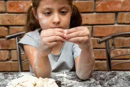 cute little girl kneading dough, preparing dough for bakingの写真素材