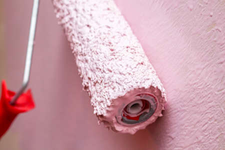 painting wall with a roller in pink colorの写真素材