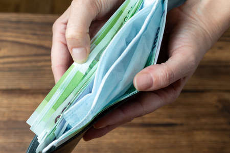 hands holding wallet with money and protective mask.