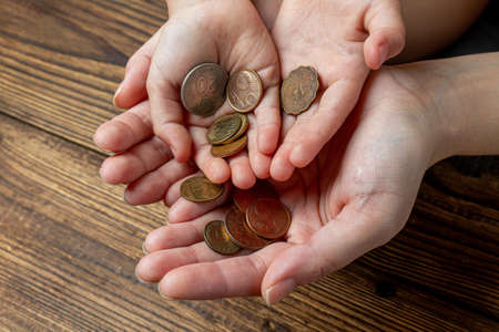 Many hands holding coins in the palms. Share, charity, family concept.の写真素材