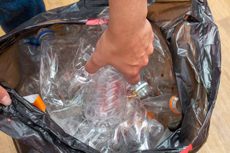 Black packet with lot of used plastic bottles for recycling in hands