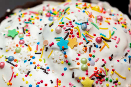 sugar glazed icing cake coating, decorated with colored candy sweets close up background