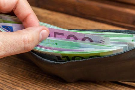 hands holding wallet full of money banknotes on wooden background