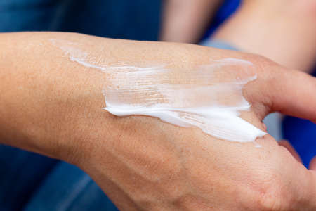 applying a white cosmetic cream on the girl hand