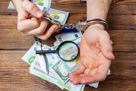 handcuffed hands on a money banknotes background.の写真素材