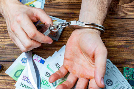 handcuffed hands on a money banknotes background.の写真素材