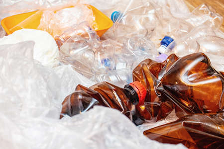 Lot of used plastic, crumpled empty bottles, packets, plastic orange dish, diaper, pollution recycle eco concept background close up selective focusの写真素材