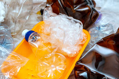 Lot of used plastic, orange container plate, crumpled empty bottles, packets, pollution recycle eco concept background close up selective focusの写真素材