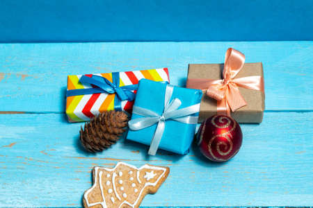 Colorful gift boxes fir, spruce toy cookies on a blue wooden background close up. The concept of preparing for the holidays New Year and Christmas.の写真素材