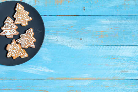 Colorful fir, spruce toy cookies in a dark dish on a blue wooden background close up. The concept of preparing for the holidays New Year and Christmasの写真素材