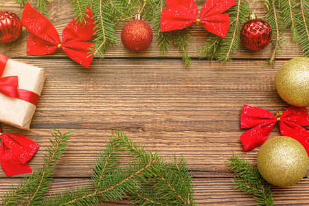 Fur spruce pine coniferous branches, sparkling shiny colorful red gold toys balls gift box bow on the brown brushed wooden backgroundの写真素材