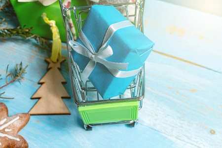 Colorful gift boxes in shopping cart on a wooden blue background. The concept of preparing for the holidays New Year and Christmas.の写真素材