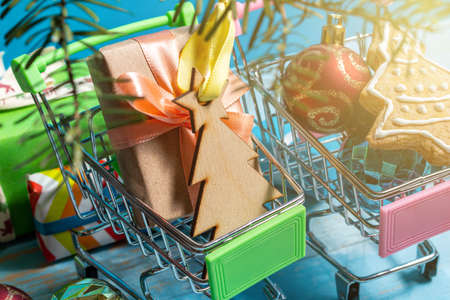 Colorful gift boxes fir, spruce, branches in shopping cart on a wooden blue background. The concept of preparing for the holidays New Year and Christmas.