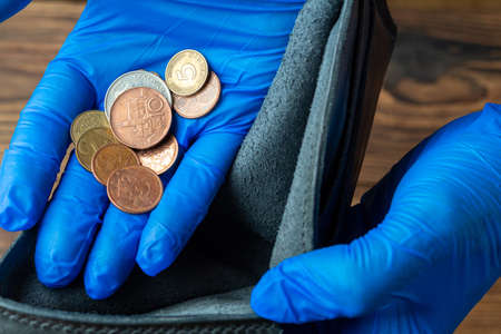 empty blue wallet in hands in medical gloves holding coins after financial economic crisis