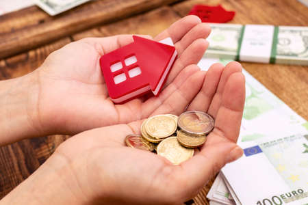 Hand holding house home and money real estate concept, real estate expenses, property expenses, buying a property mockup copy space close up backgroundの写真素材