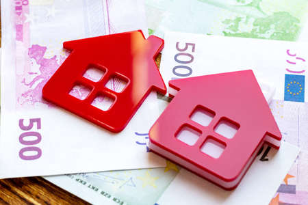 Red home house on the banknotes background euro dollar pile pack real estate concept expenses...
