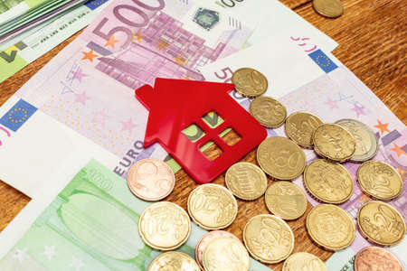 Red home house on the banknotes background euro dollar pile pack real estate concept expenses property buying mockup copy space close up background selective focusの写真素材