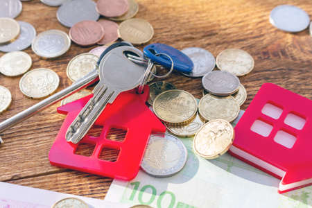 Red home house keys on the banknotes and coins background euro pile pack real estate concept expenses property buying mockup copy space close up background selective focusの写真素材