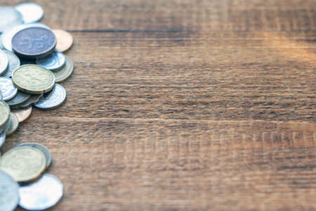 a pile of coins on a wooden background with space for an inscription copy spaceの写真素材