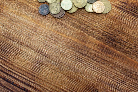 a pile of coins on a wooden background with space for an inscription copy space
