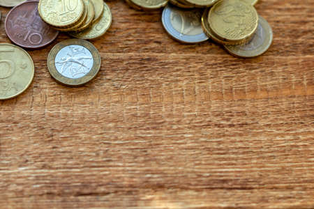 a pile of coins on a wooden background with space for an inscription copy spaceの写真素材