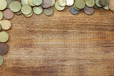 a pile of coins on a wooden background with space for an inscription copy spaceの写真素材