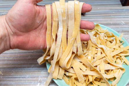 Homemade pasta preparation process with hands and rolling pinの写真素材