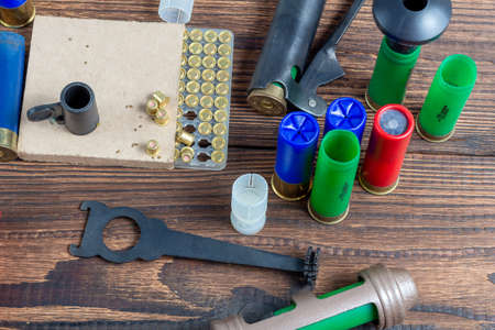 reloading process shotgun shells with special reload equipment. Powder, bullets, fraction, shells, buckshot on the wooden backgroundの写真素材