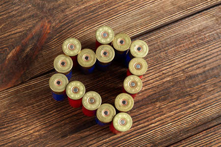 12 gauge caliber color cartridges hunting shells heart shape love on a brown wooden background