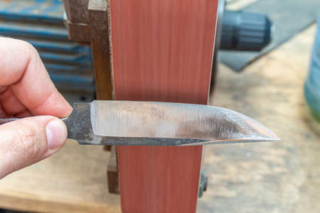 Grinding polishing sharpening knife blade on the belt grinder sander equipment. Knife making.