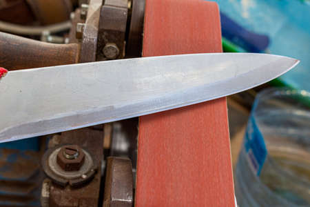 sharpening polishing kitchen knife blade on the belt grinder sander equipment. Knife making.