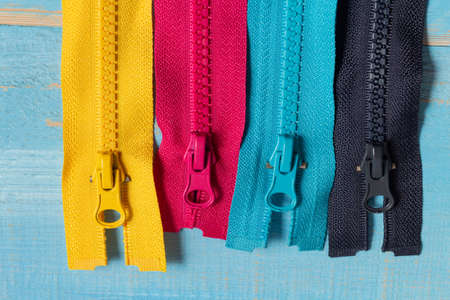 Pack lot of colorful plastic and metal zippers stripes with sliders pattern for handmade sewing tailoring on the blue denim background close up selective focusの写真素材