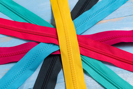 Pack a lot of colorful plastic zippers stripes with sliders pattern for handmade sewing tailoring on the blue denim background close up selective focusの写真素材