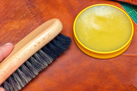 Polishing handmade leather bag with brush and wax