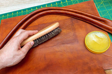 Polishing handmade leather bag with brush and wax