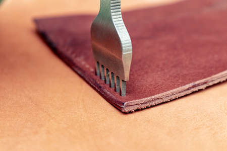 Making holes in leather with puncher tool. Sewing wallet.