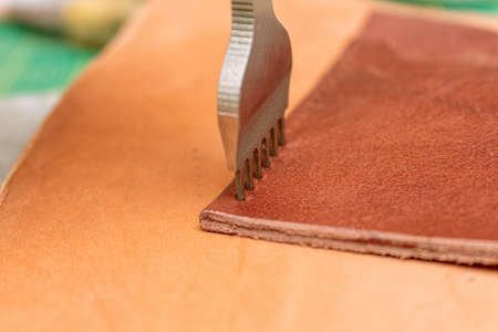 Making holes in leather with puncher tool. Sewing wallet.