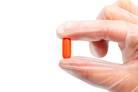 colorful pill, tablet in hand in a medical glove isolated. Drug protection, treatment of viruses, antiviral, diseases concept.の写真素材