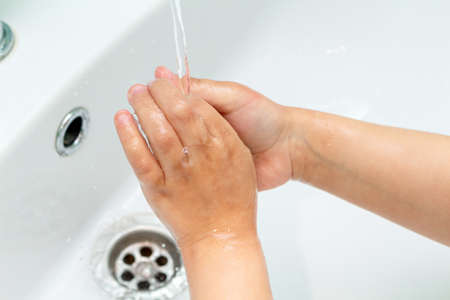 small kid, child washes his hands under the tap in the sinkの写真素材