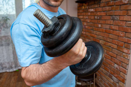 dumbbell in the man hand doing fitness sport exercise at home close up