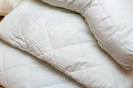 White and beige packed pile of the linen bedclothes blanket with pillow and bedding sheetsの写真素材