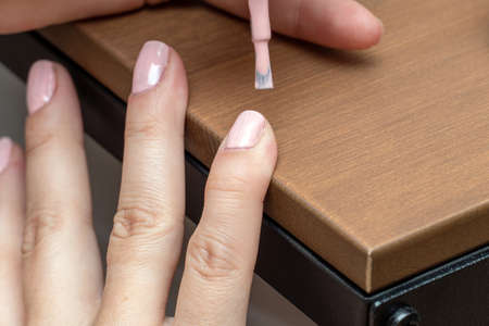 Applying pink nail polish gel, varnish with brush during manicure processの写真素材