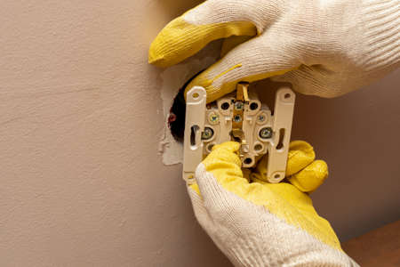 Replacing, installing an electrical socket, outlet with hands in protective rubber glovesの写真素材