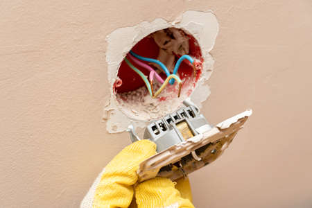 Replacing, installing an electrical socket, outlet with hands in protective rubber gloves