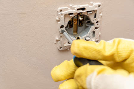 Replacing, installing an electrical socket, outlet with hands in protective rubber gloves