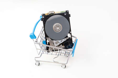 Open hard disk drive in shopping cart. Information, data storage infrastructure cost concept.