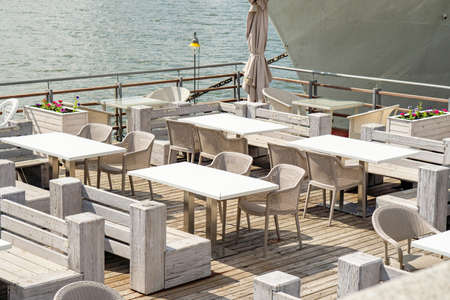 Empty tables in restaurant on barge on river, sea during quarantine