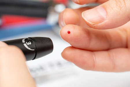 Taking blood for diabetes sugar level medical test from finger